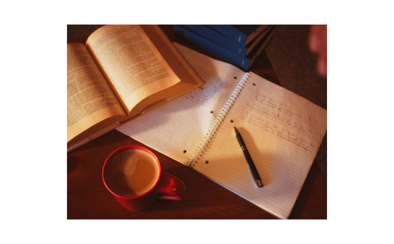 Coffee, books and writing on the desk.